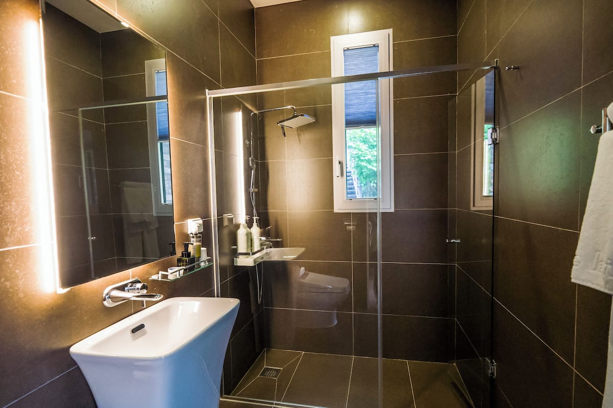 A modern bathroom with a glass-enclosed shower, a white sink, and a mirror.