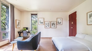 Una camera da letto con un letto, una scrivania con sedia, un divano e quadri appesi al muro.