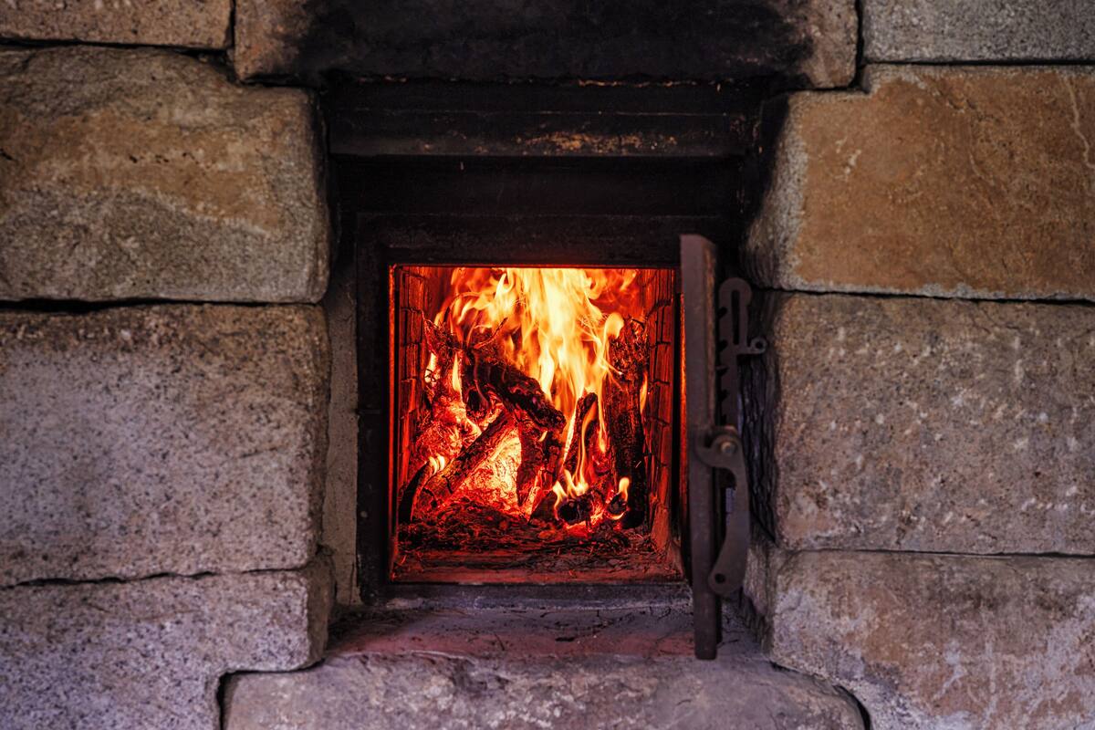 A stone fireplace with a fire burning inside.