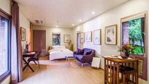 Camera d'albergo con un letto, una scrivania, un divano, un tavolo da pranzo e quadri appesi alle pareti.