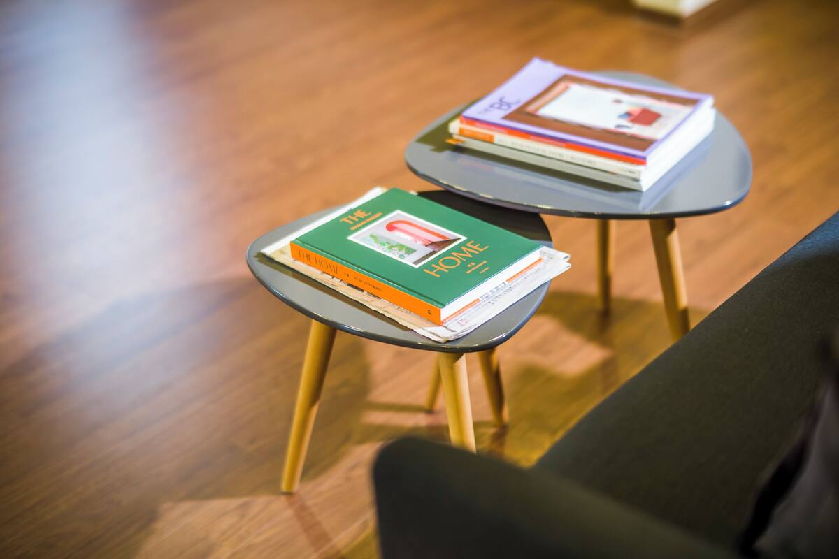 Two small tables with books on them, placed on a wooden floor.