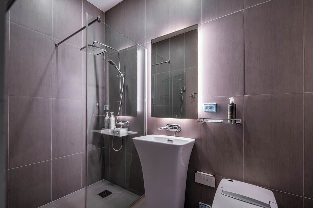 A modern bathroom with a glass-enclosed shower, a white sink, and a mirror above it.