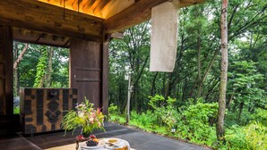 Un'area pranzo all'aperto con un tavolo apparecchiato per due, circondata da vegetazione lussureggiante e vista sulla foresta.