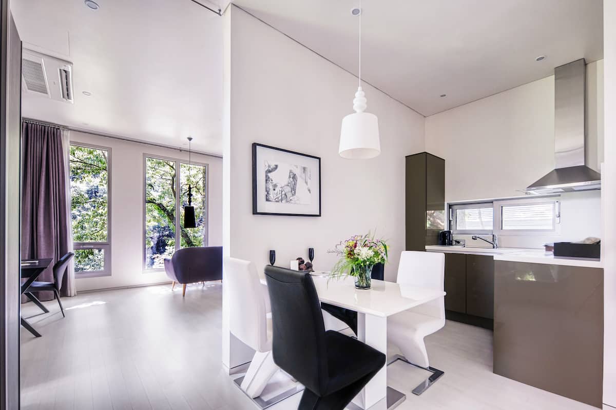 A modern kitchen with a dining area, large windows, and a pendant light.