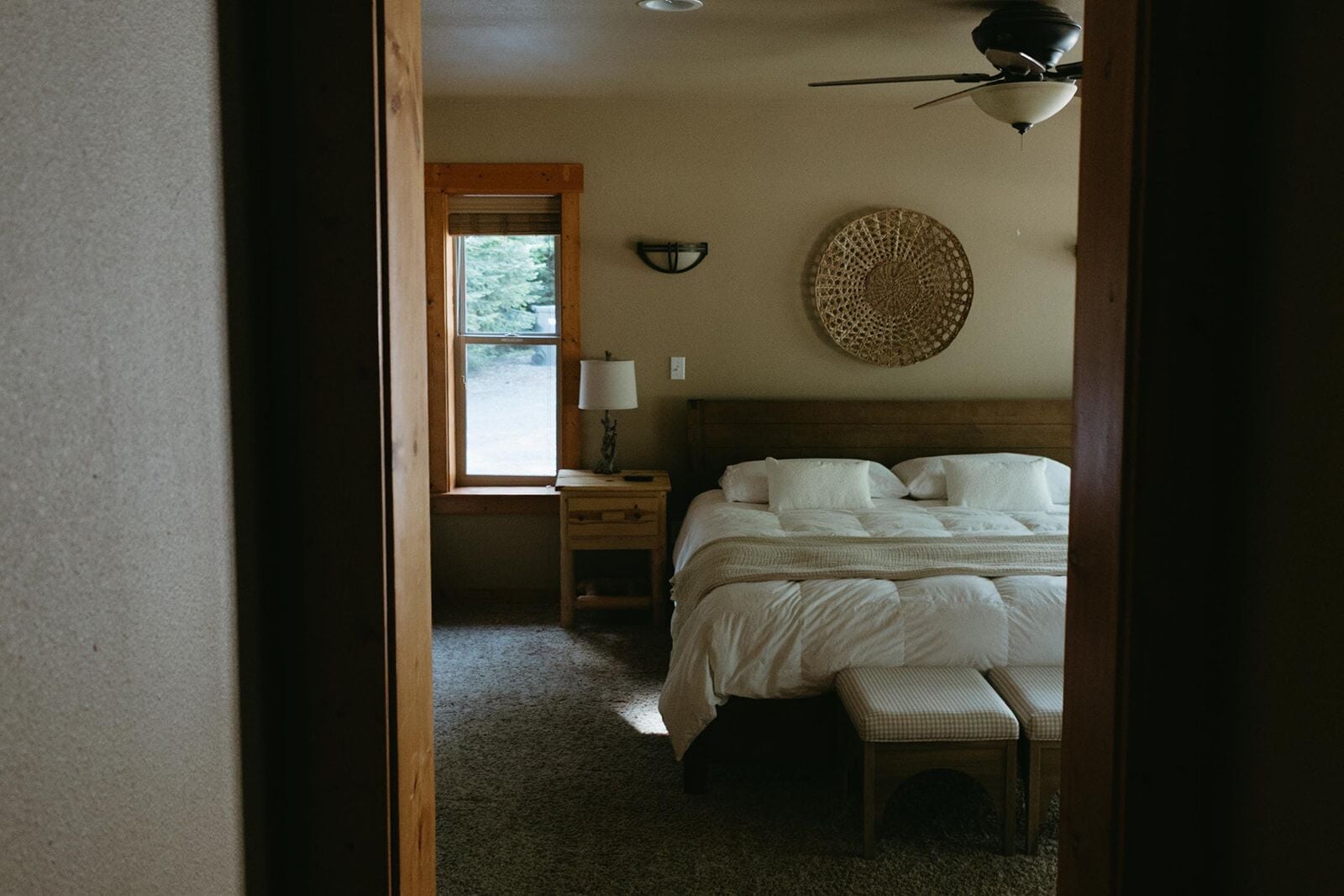 A bedroom with a bed, bedside table, lamp, and a wall-mounted decorative item.