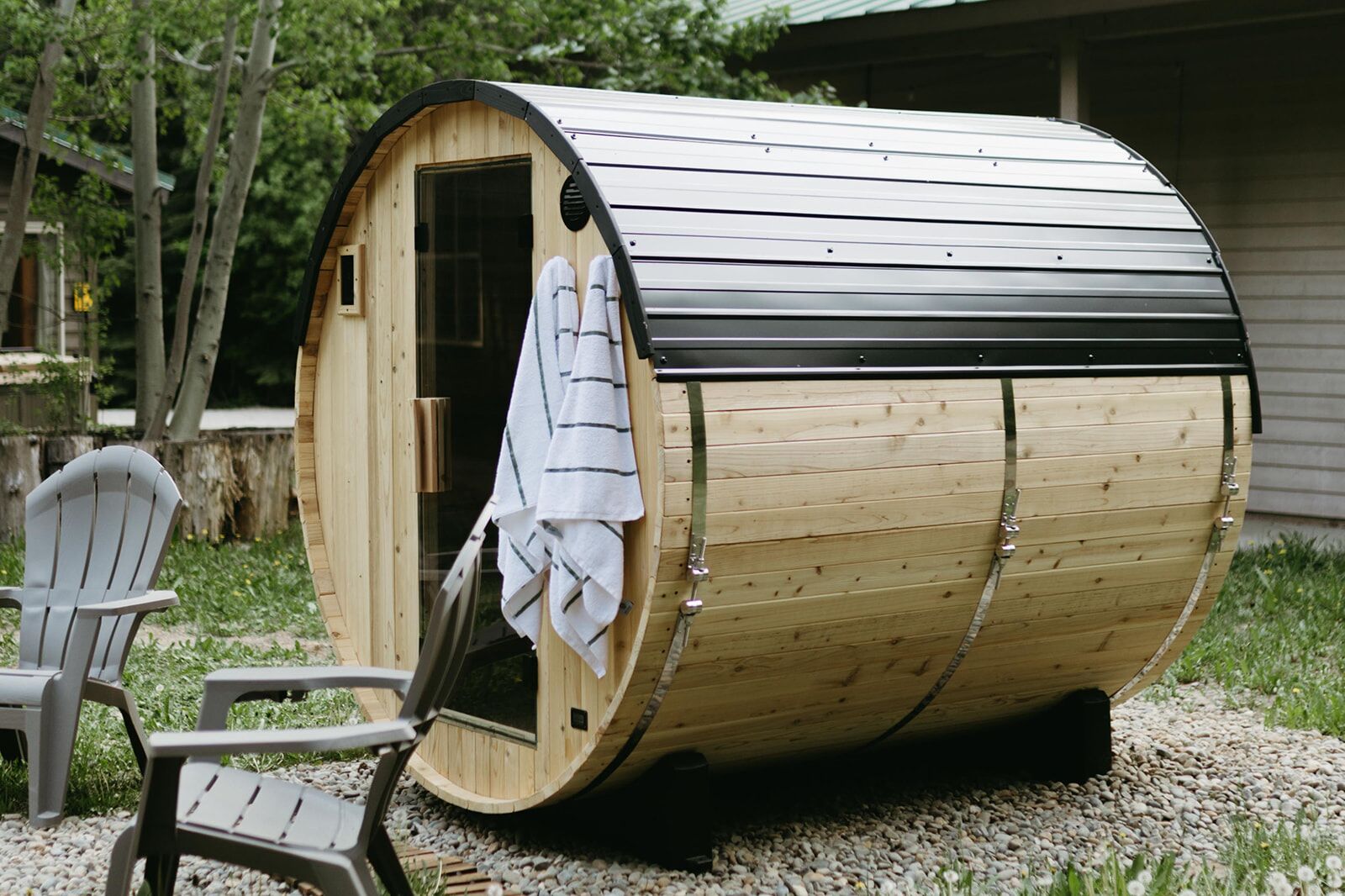 A wooden sauna with a curved roof, a door, and a bench outside.