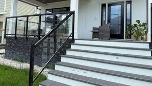 Moderni talo, jossa on kivestä rakennettu portaikko, katettu kuisti ja liukuovet.