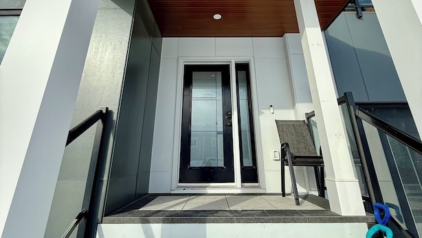 Une entrée moderne, avec un plafond en bois, des colonnes blanches et une porte en verre.