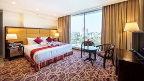 Habitación de hotel con una cama grande, un escritorio, una silla y un televisor.