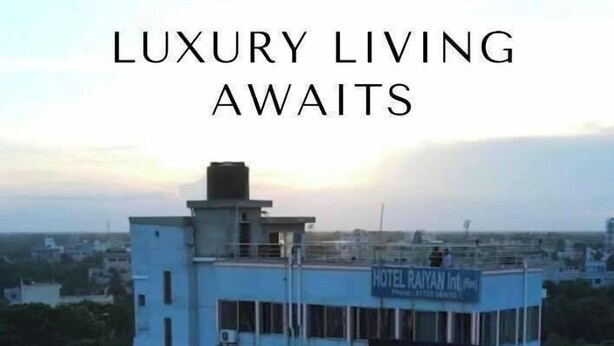 Un edificio de varios pisos con un letrero que dice 'Hotel Rayan Int.' y un logotipo con una 'R' mayúscula en el centro.