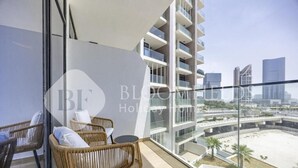 Un balcón con mobiliario de mimbre y vista a un conjunto moderno de edificios.