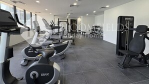 Un gimnasio con cintas de correr, elípticas y equipo de levantamiento de pesas.