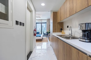 A modern kitchen with a marble countertop, wooden cabinets, a stainless steel sink, and a coffee maker. - Bloomfields Fantastic Stu Maryah (Abu Dhabi)