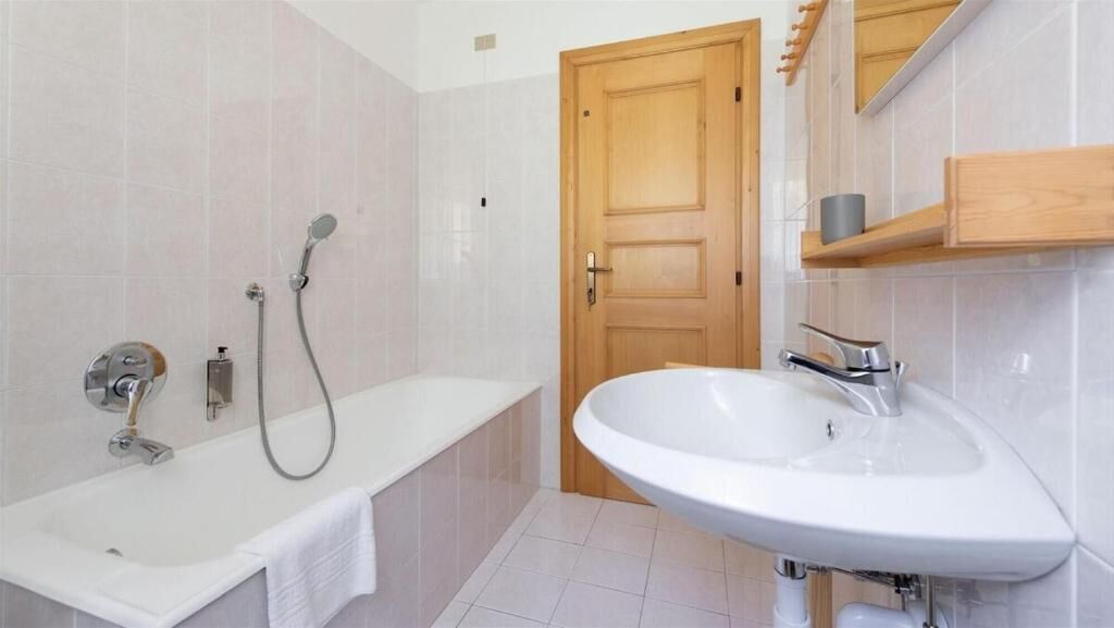 A bathroom with a bathtub, a sink, and a wooden door.