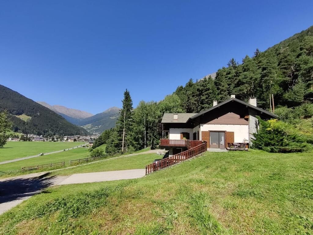 A house with a wooden deck, a small porch, and a view of a mountain range.