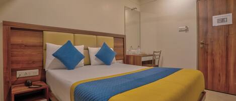 A neatly arranged hotel room with a bed, bedside table, and a desk with a chair.