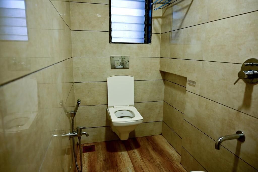 Et lille badeværelse med fliser, toilet, brusebad og et vindue.