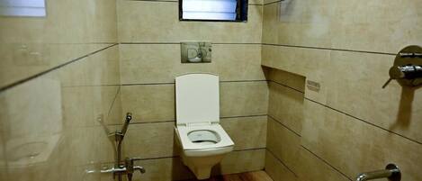 Un baño pequeño con azulejos, un inodoro, una ducha y una ventana.