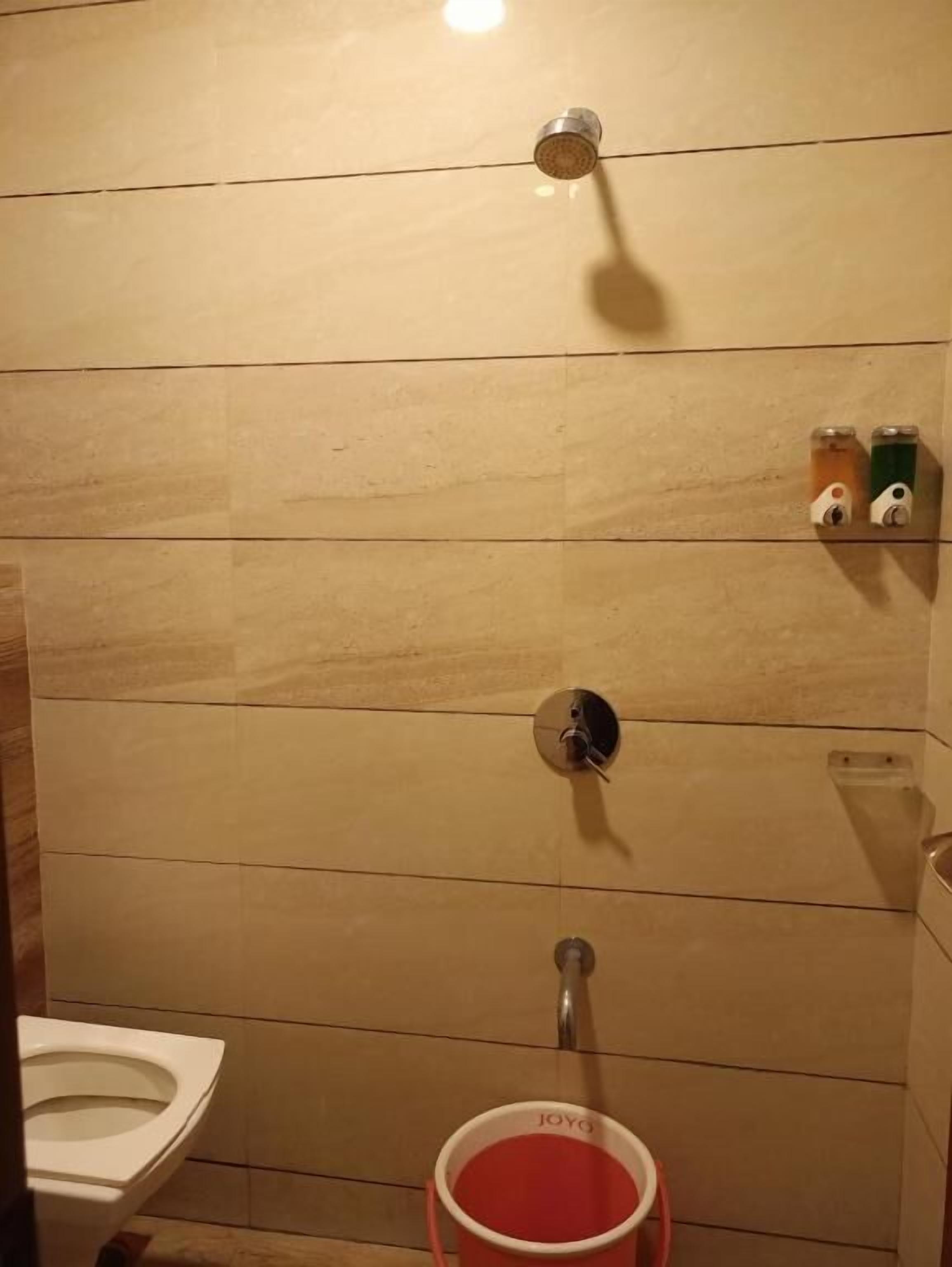 A small, tiled bathroom with a toilet, a shower, and a hand dryer.