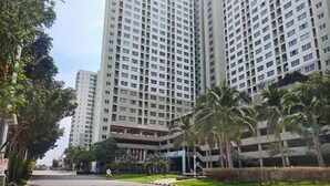 Un edificio residencial de varios pisos con un patio central, rodeado de follaje y palmeras.