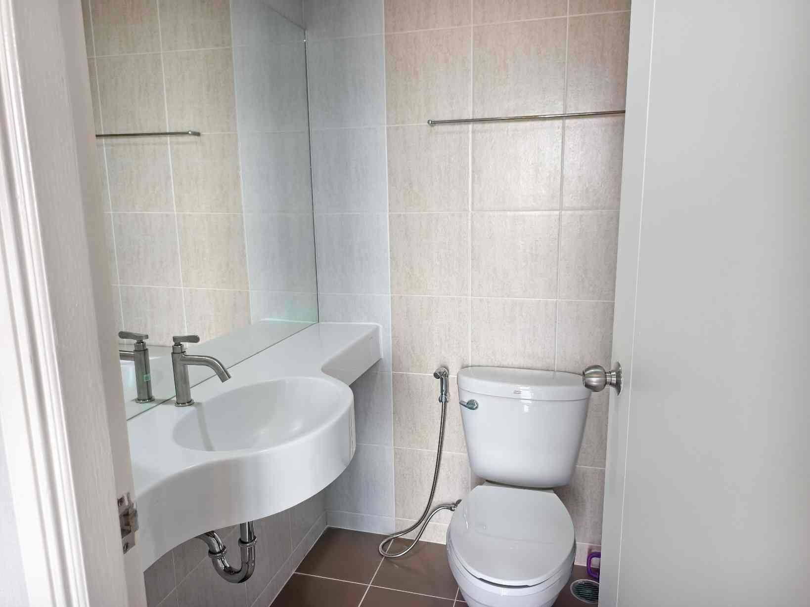 Et lille, rent badeværelse med en hvid vask, toilet og brusebad.