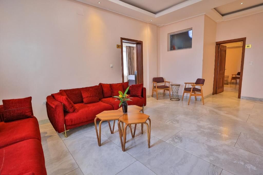 A spacious lobby with a red sofa, two wooden tables, and a small potted plant.