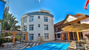 Um hotel com piscina, área de estar externa e uma mistura de arquitetura moderna e tradicional.