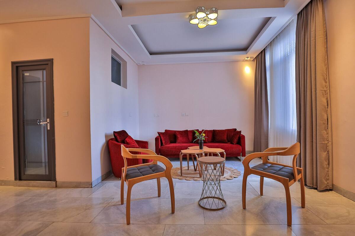 Un salon comprenant un canapé, deux fauteuils, une table basse et un luminaire suspendu au plafond.