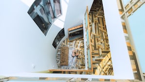Interior moderno com parede estampada em padrão geométrico, uma escada e uma janela grande.