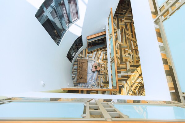A modern interior with a geometric patterned wall, a staircase, and a large window. - Homefree Hotel by signature (Kigali)