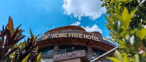Ein Hotel mit geschwungener Fassade und einem Balkon, mit der Aufschrift "HOME FREE HOTEL".