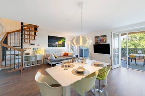 Ein zeitgemäßer Wohnraum mit Treppe, Essbereich und großen Fenstern.