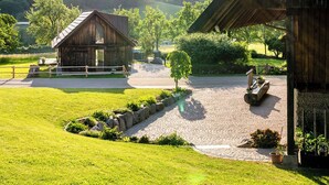 A rustic wooden building with a stone pathway leading to it, surrounded by lush green grass and trees.