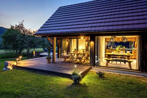 A modern house with a deck, a dining area, and a kitchen visible through glass doors. - Modern converted barn with whirlpool in beautiful natural surroundings (Gutach (Schwarzwaldbahn))