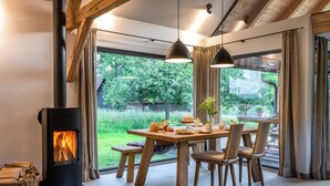 A cozy dining area with a fireplace, wooden furniture, and large windows offering a view of the outdoors.