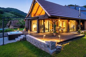 Een houten hut met een terras, buitenmeubels en een jacuzzi.