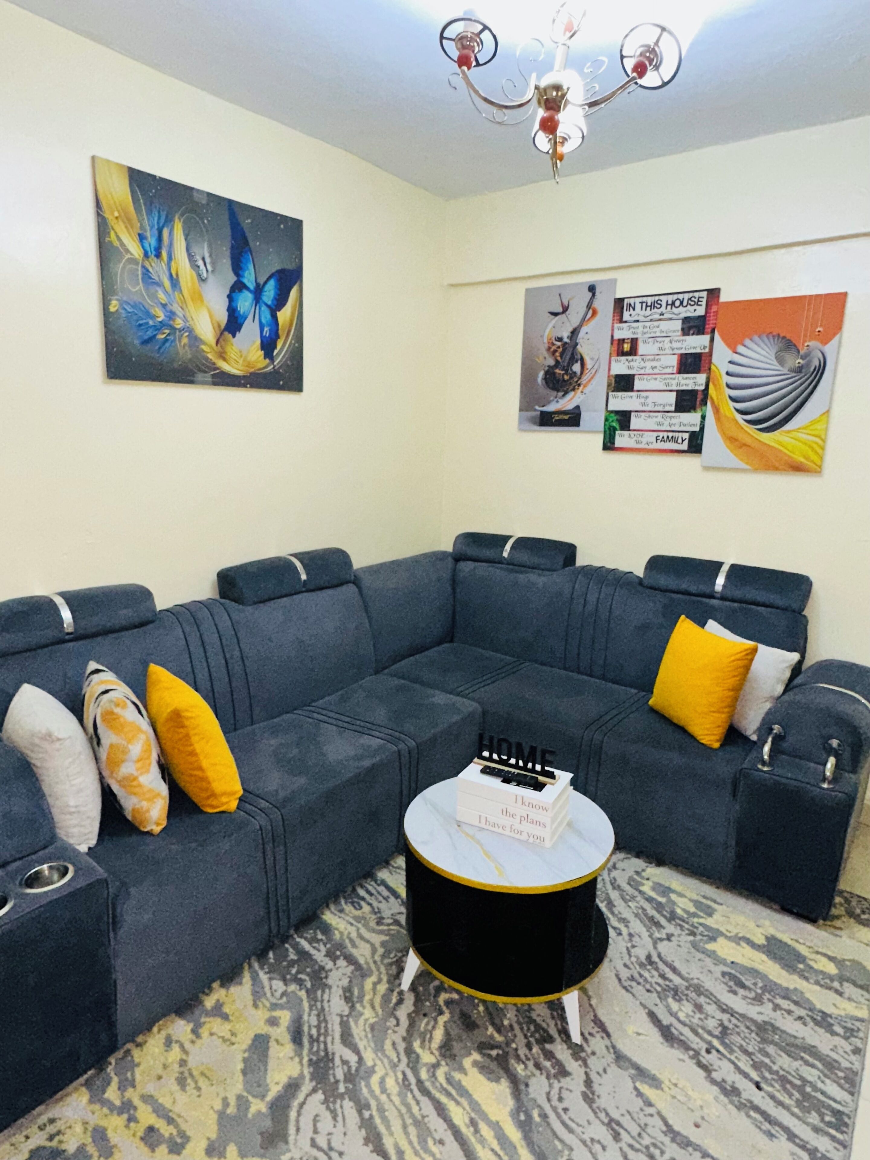 A modern living room with a sectional sofa, a round coffee table, and a chandelier.