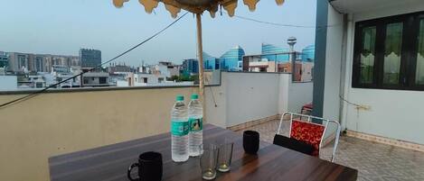 Una mesa de madera con dos botellas de agua y dos vasos en un balcón con piso estampado.