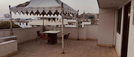 Une terrasse sur le toit, dotée d’un sol à motifs, d’une table, de chaises et d’une structure ressemblant à une tente.