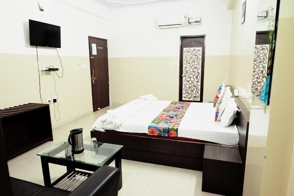 Une chambre d’hôtel avec un lit, une petite table avec une cafetière, un téléviseur fixé au mur et un appareil de climatisation.