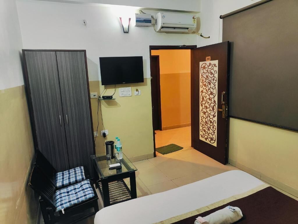 Habitación de hotel con cama, escritorio con silla, armario, televisor y aire acondicionado.