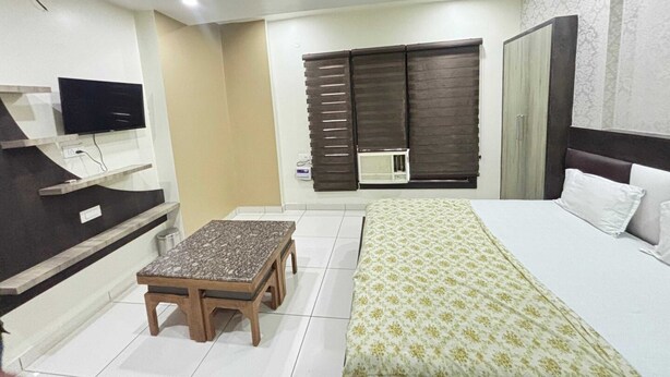 A hotel room with a bed, a TV, a desk, and a window with blinds. - Townhouse Dharuhera Bus Terminal (Rewari)