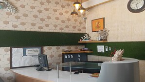A hotel reception desk with a check-in counter, a clock, and a framed picture on the wall. - Townhouse Dharuhera Bus Terminal (Rewari)