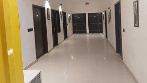 A hotel corridor with multiple doors, a vent on the left, and pendant lighting. - Townhouse Dharuhera Bus Terminal (Rewari)