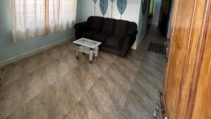 Een woonkamer met een bank, een salontafel en een muur met bladmotieven.