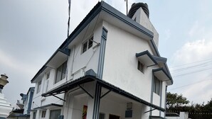 Een huis met twee verdiepingen, een betegeld terras, een balkon en een schoorsteen.