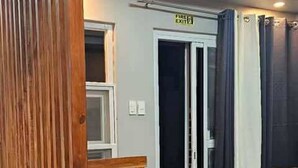 A room with a wooden partition, a fire exit sign, a door, and a fan. - MEEK'S VILLAS TRANSIENT HOUSE (Baguio)