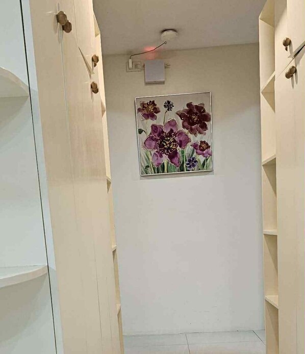 A hallway with a framed floral artwork on the wall, a ceiling light, and a smoke detector. - MEEK'S VILLAS TRANSIENT HOUSE (Baguio)