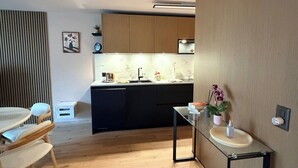 Uma cozinha moderna com armários de madeira, bancada preta e mesa de vidro com pia.