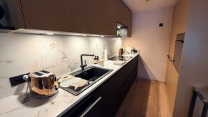 Uma cozinha moderna com bancada de mármore, pia preta e máquina de café.